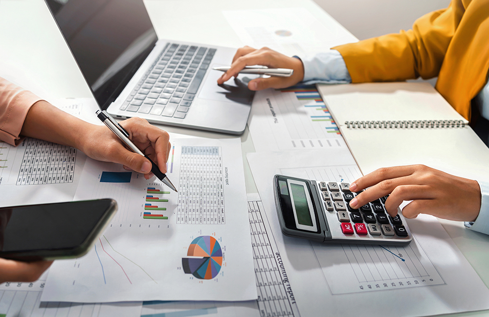 Investor working on charts and typing on calculator